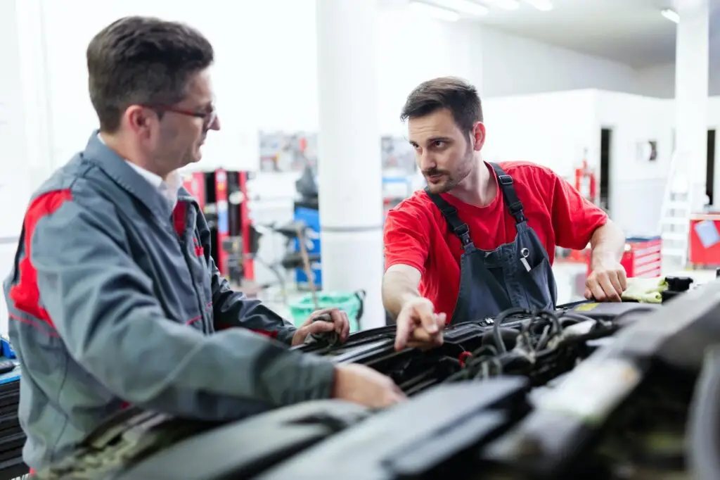 Mechanics working on a car repair at an MOT test centre in Southall, West London