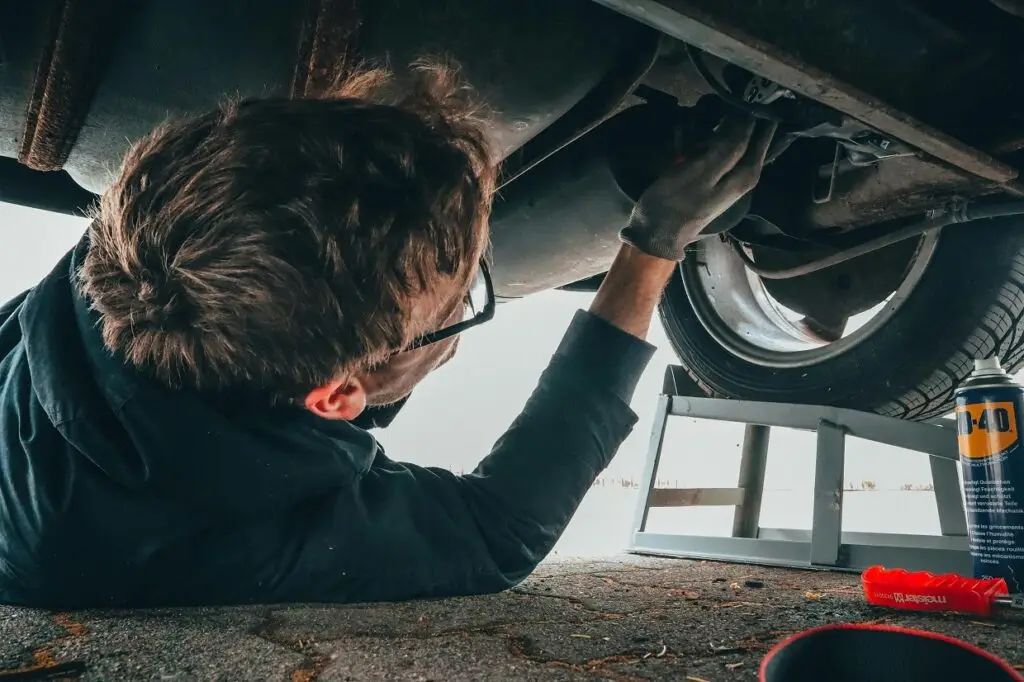 Mechanic performing brake service under car, including brake pad replacement and brake fluid change, using high-quality OEM parts