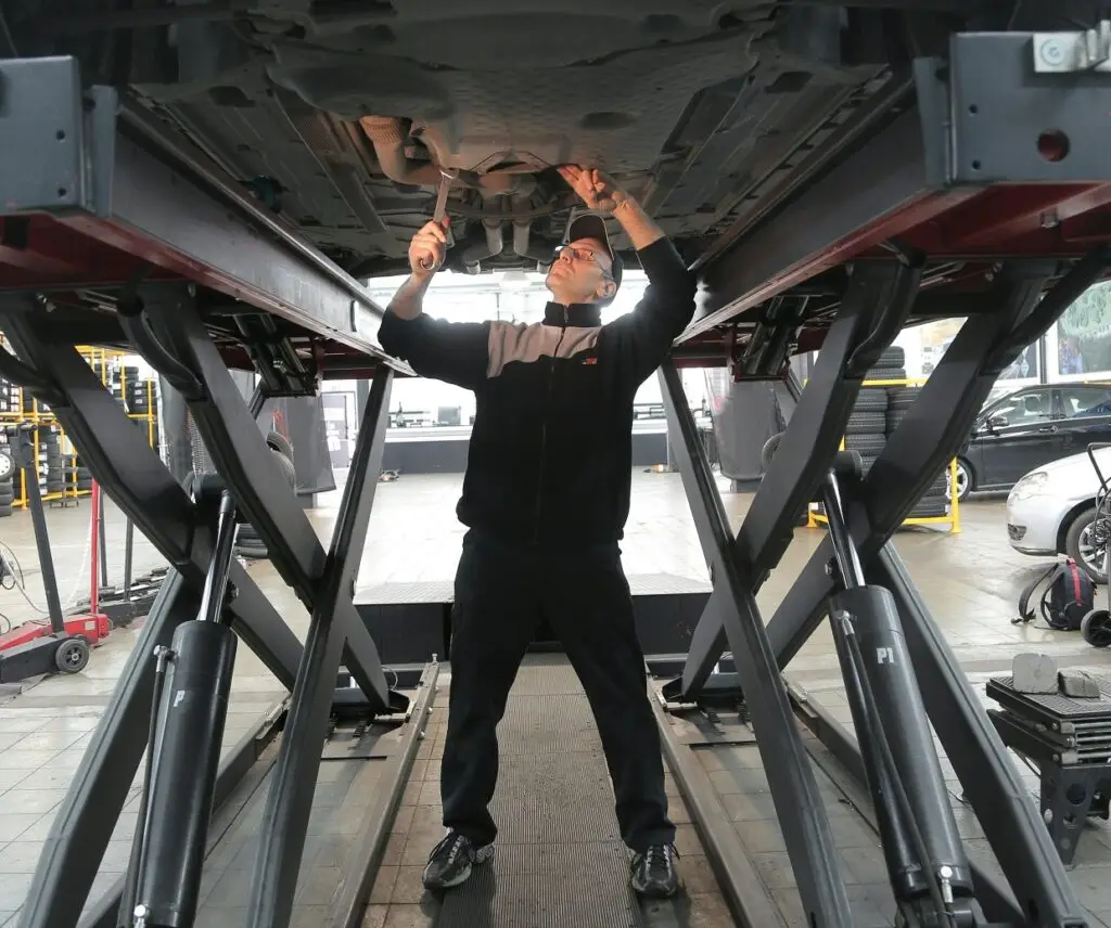 Mechanic performing exhaust repair on a vehicle at Southall Autos and Tyres, showcasing pricing details for minor repairs, muffler replacements, and full exhaust system replacements.