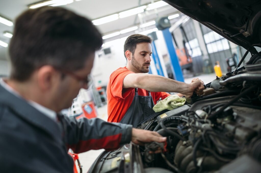 Mechanics performing car repair and maintenance at MOT test centre in Southall